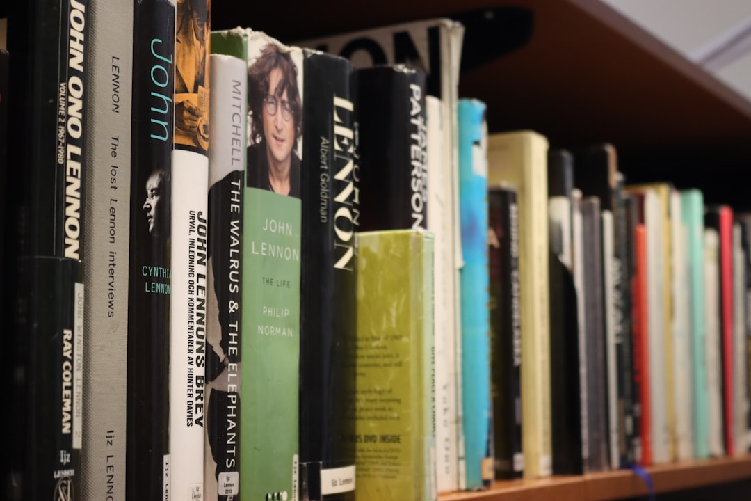 A bookshelf filled with books, some featuring john lennon.