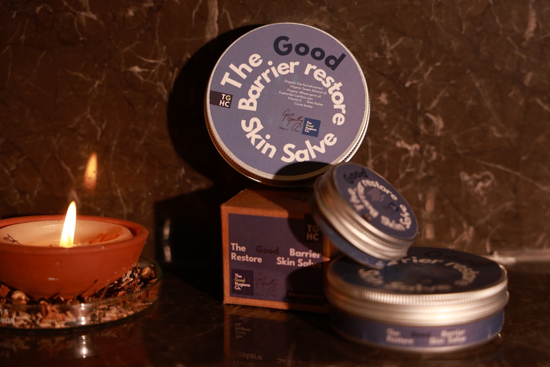 Skin salve tins and lit candle on marble surface