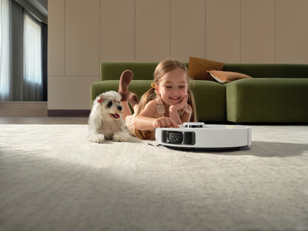 Girl and dog watch robot vacuum cleaner