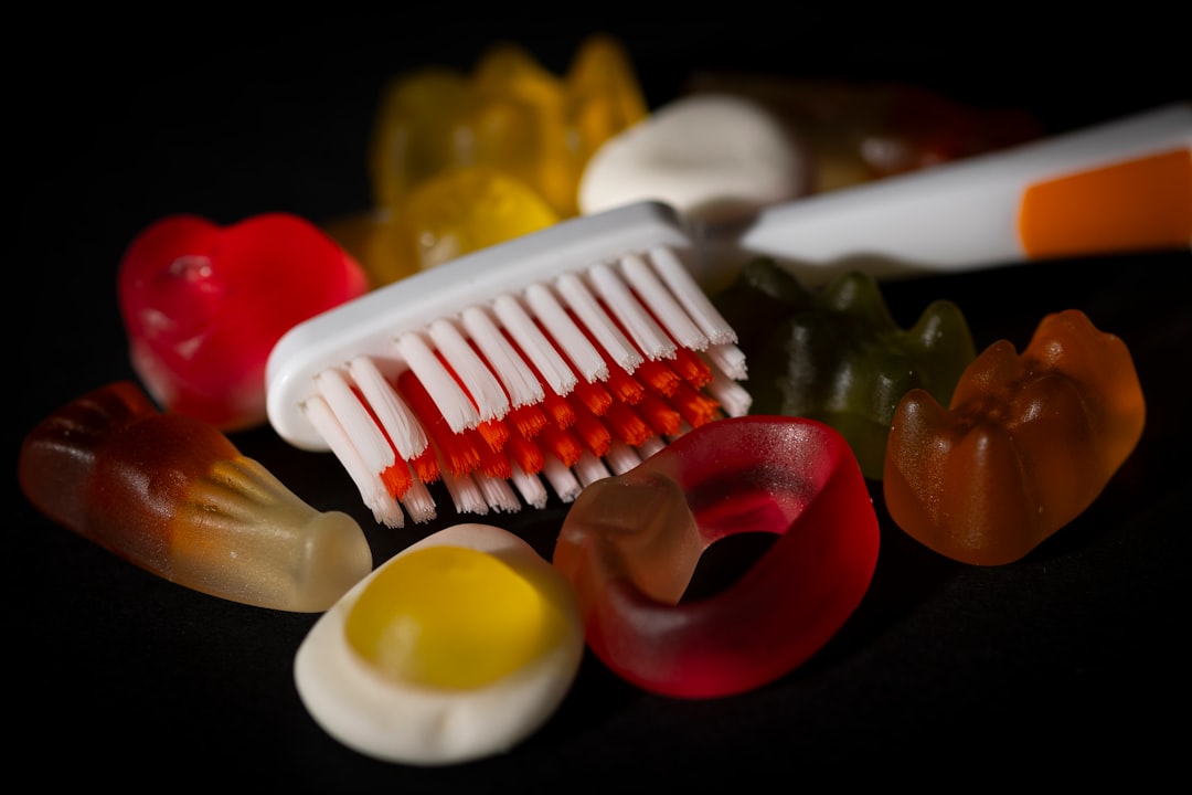Gummy candies surround a toothbrush on black background