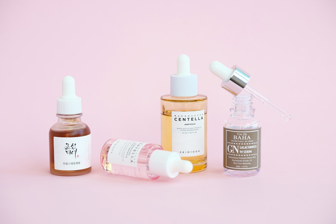 Skincare serums and dropper bottles sit on pink.