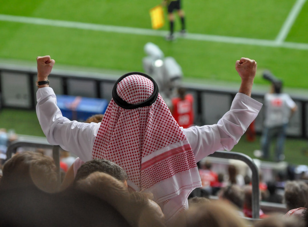 Man in traditional arab clothing cheering at soccer game