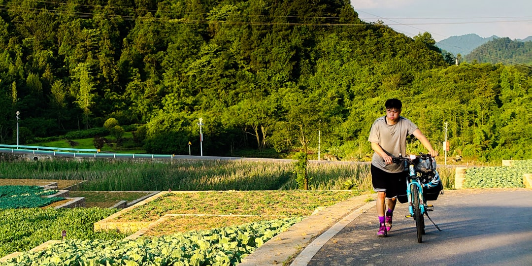 man in gray t-shirt and black shorts walking on gray concrete pathway during daytime