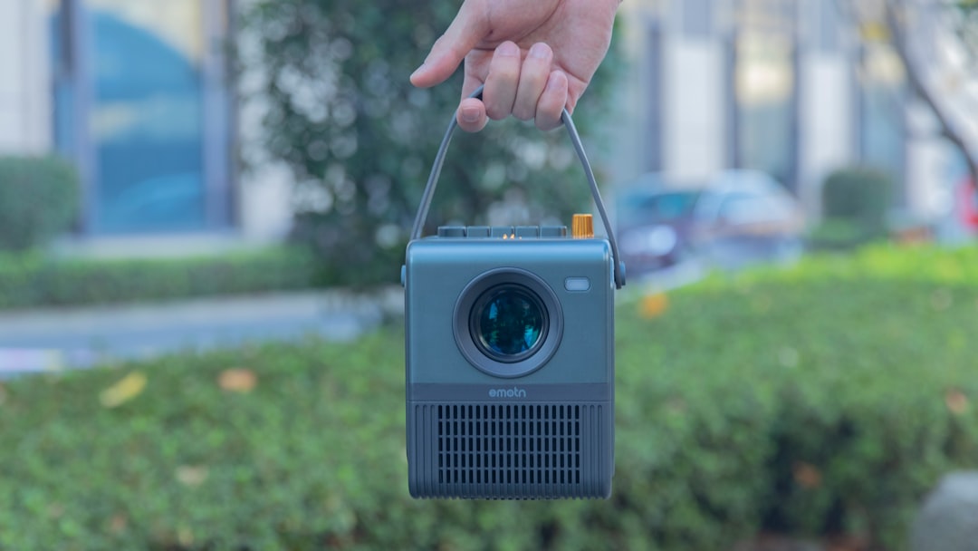 a hand holding a small camera in front of a building