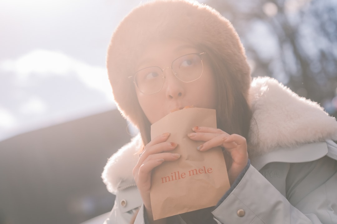Woman in fur hat drinks from paper bag.