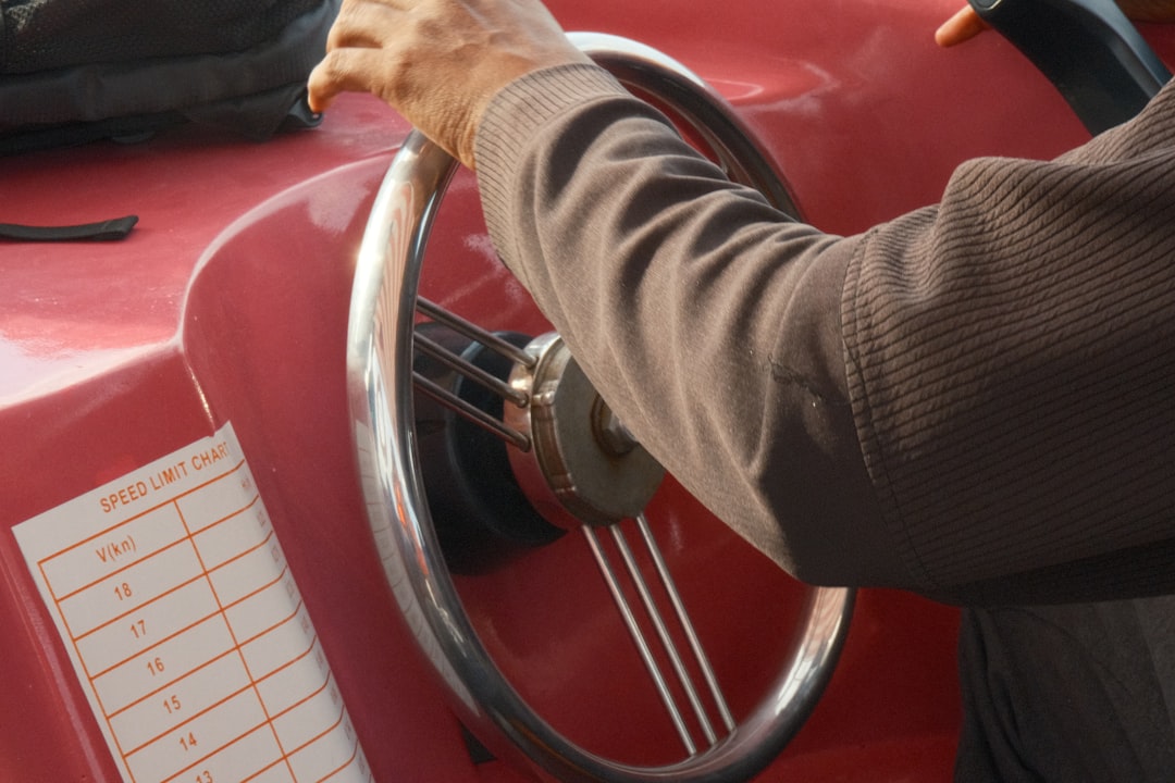 Person holding a steering wheel in a red vehicle.