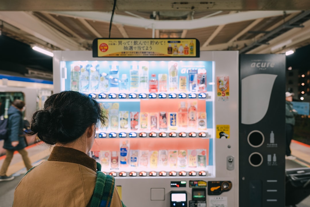 Woman choosing a drink from a brightly lit vending machine.