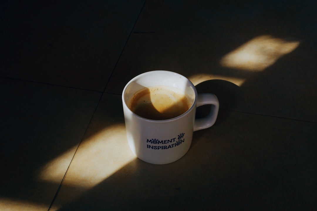 A white mug of coffee with sunlight streaming on it.