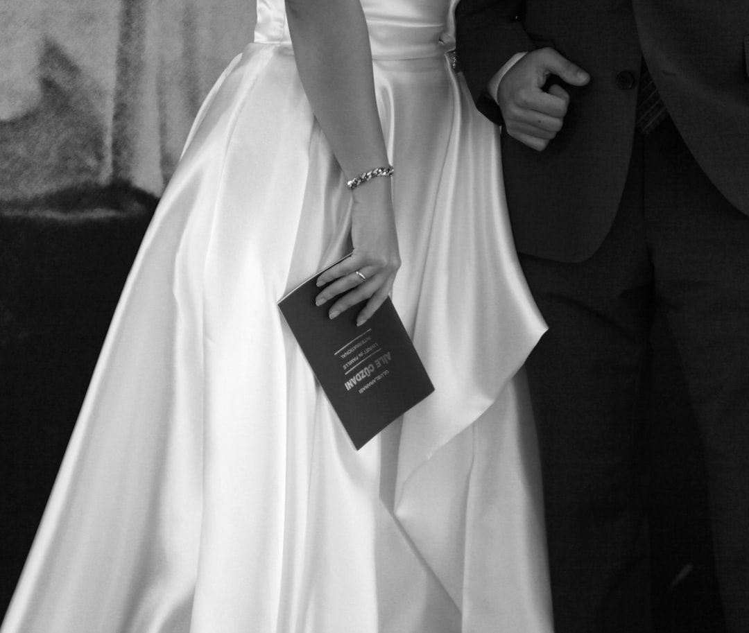 Bride in a white dress holding a dark invitation.