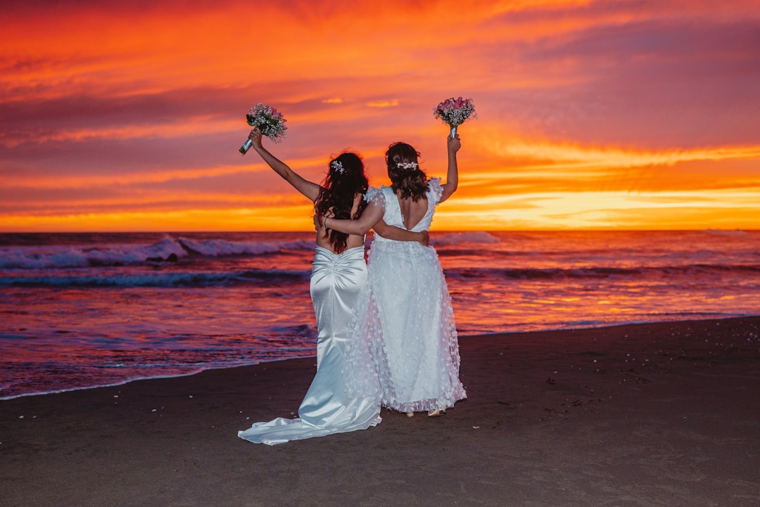 Two brides celebrating on a beach at sunset