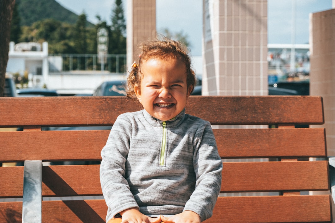 a young child sitting on a wooden bench