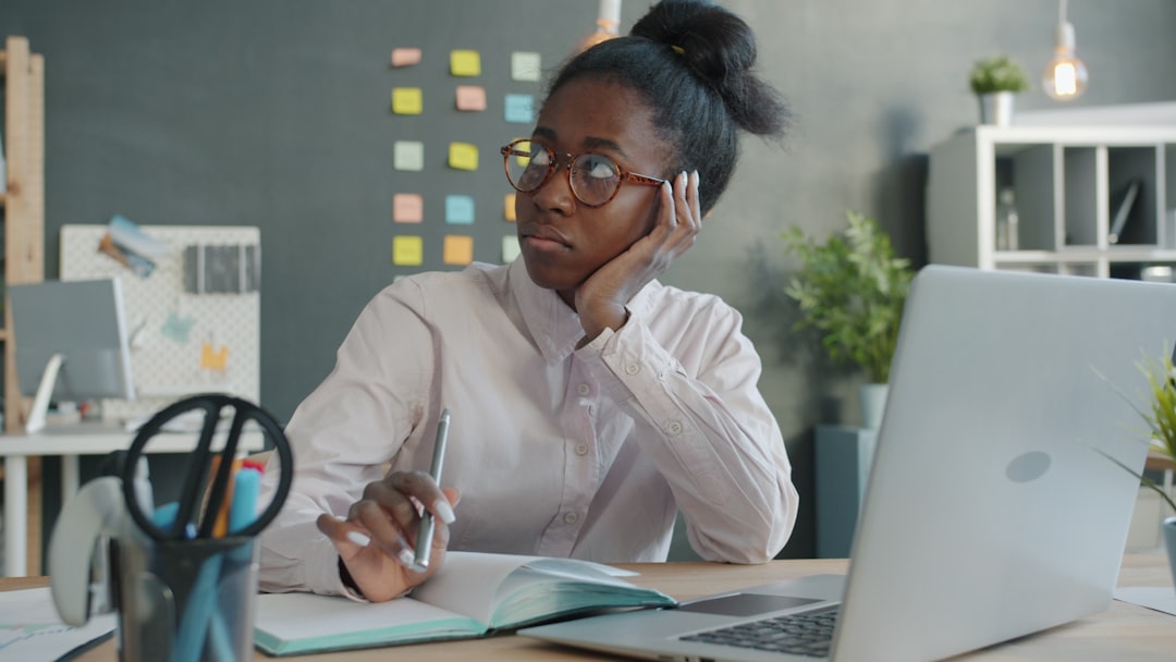 Woman looking away from laptop at desk