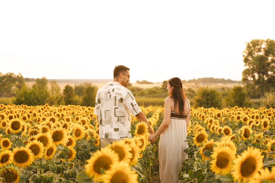 A couple walks through a sunflower field.