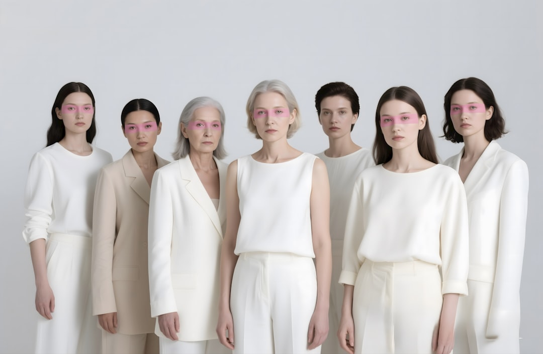 Women stand together, all in white outfits.