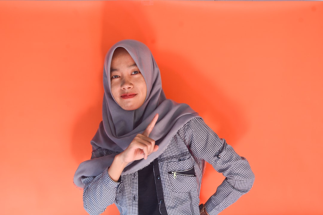 Young woman in hijab pointing finger at camera