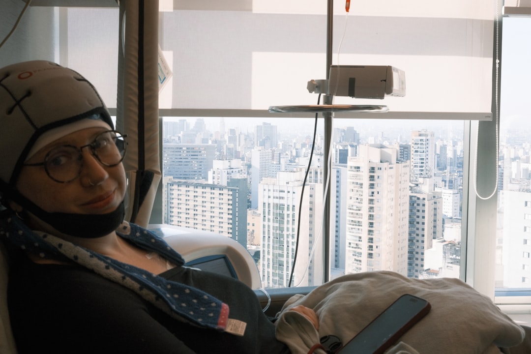 Woman in medical cap sits by window overlooking city.