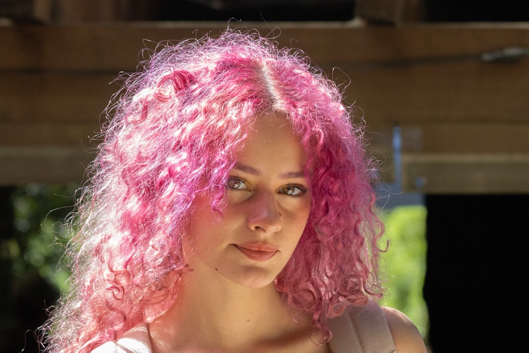 Young woman with vibrant pink curly hair outdoors