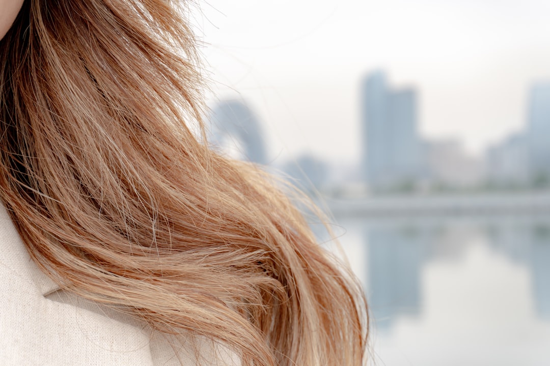 Long hair against a blurred city backdrop.