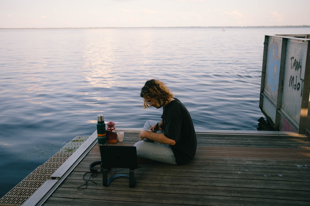 a woman sitting on a dock next to a bottle of wine
