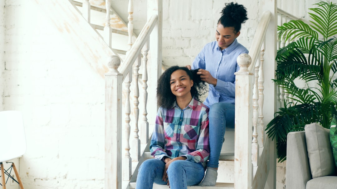 Mother braiding daughter's hair on staircase
