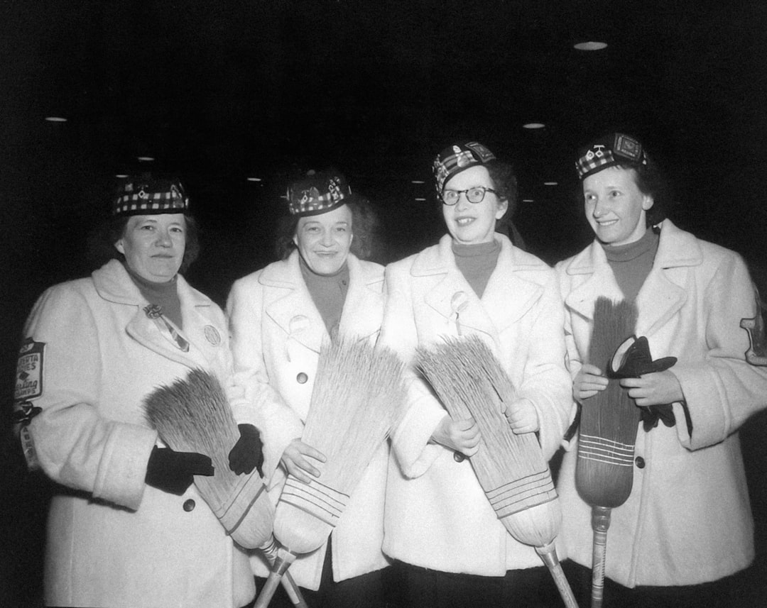 a group of women standing next to each other holding brooms