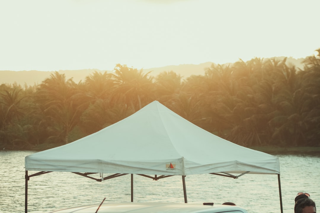 White tent beside a calm body of water at sunset