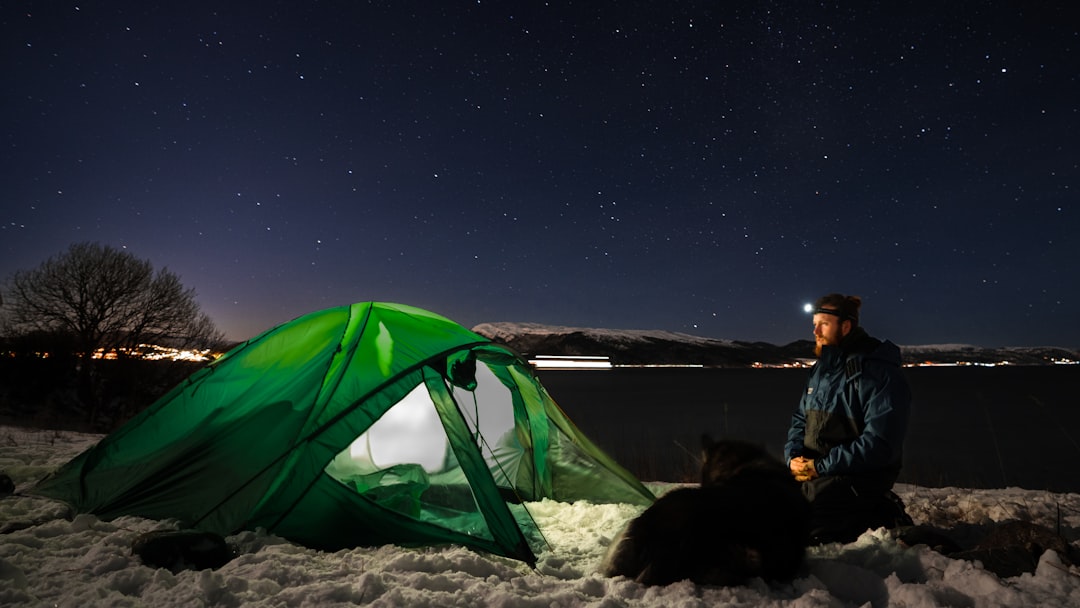 a man sitting next to a tent in the snow