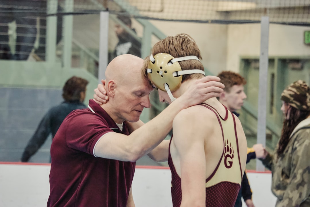 Coach and wrestler embrace after match.
