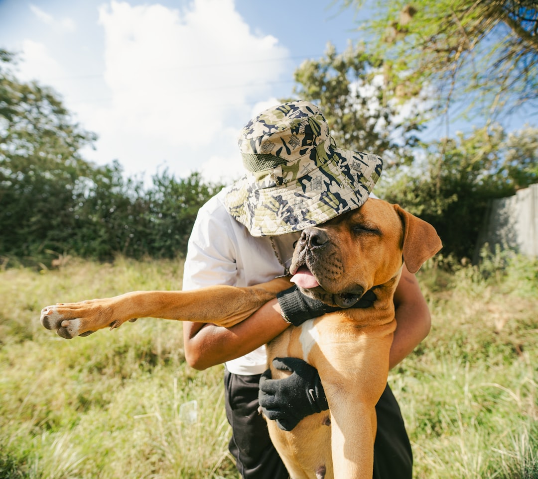 A man hugs a large dog outdoors.