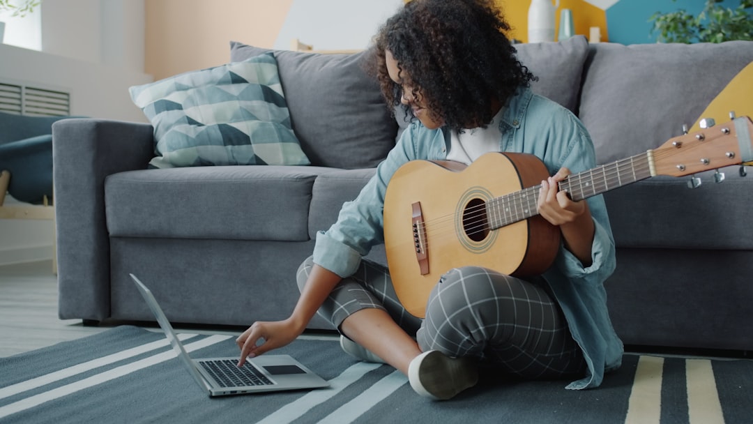 Woman learning guitar from laptop at home