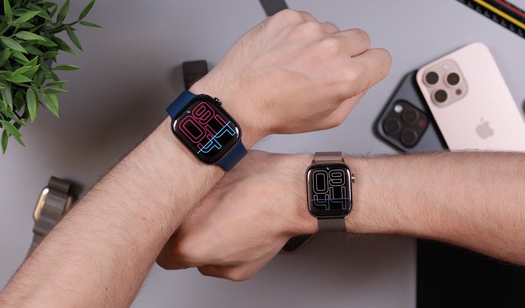 Two wrists wearing smartwatches with digital displays.