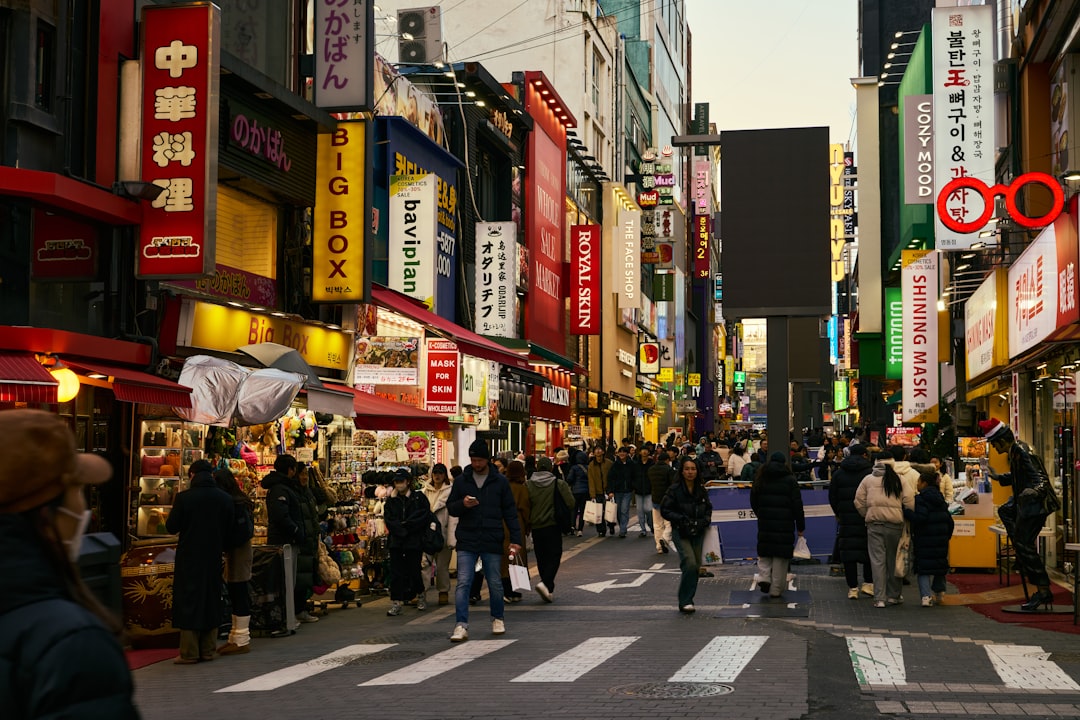 People walking down a busy street with shops and signs.