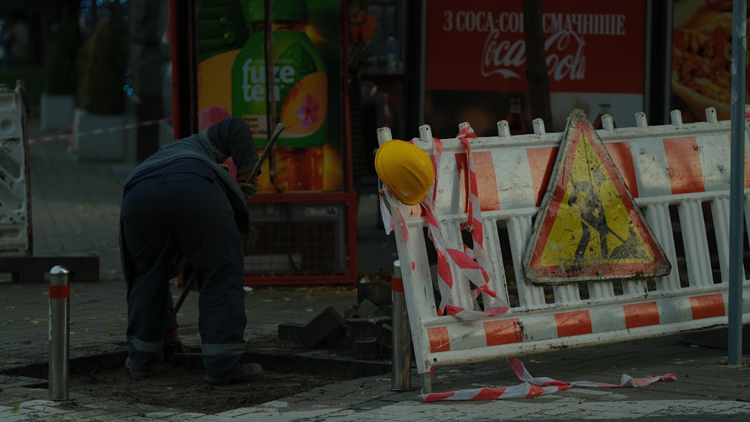 Worker digging on street with construction barriers