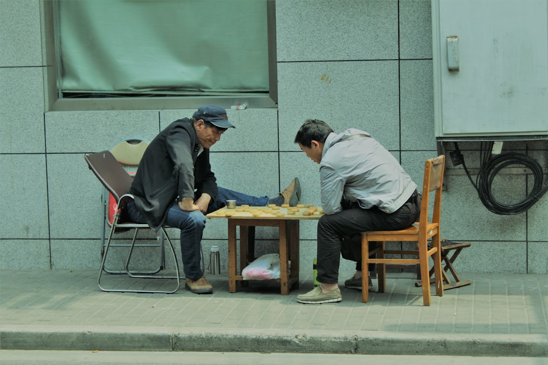 man in gray long sleeve shirt sitting on chair beside man in gray long sleeve shirt