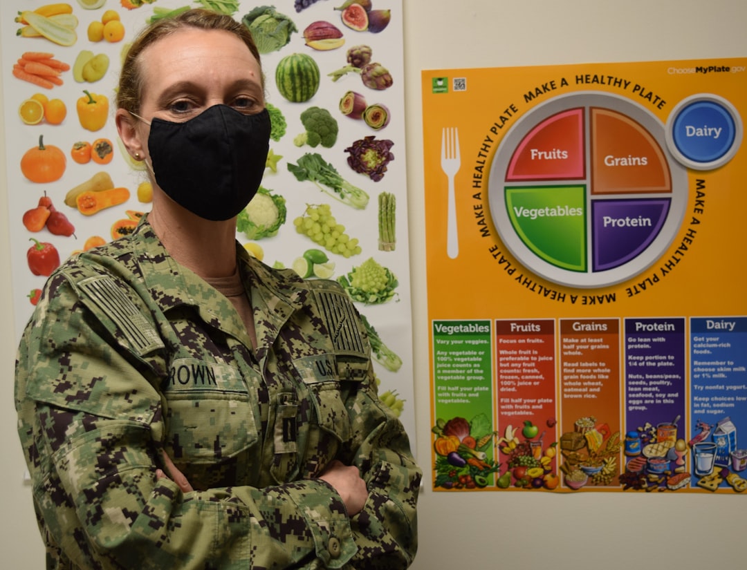 Woman in uniform stands by a healthy eating plate poster
