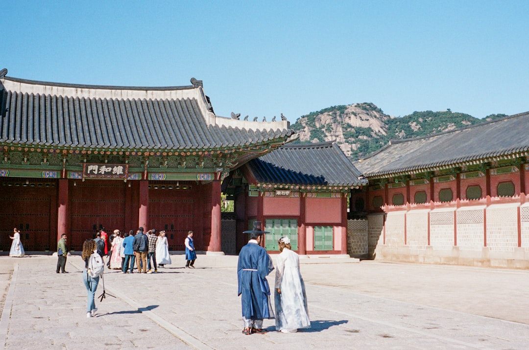 People in traditional korean clothing at a historic palace.