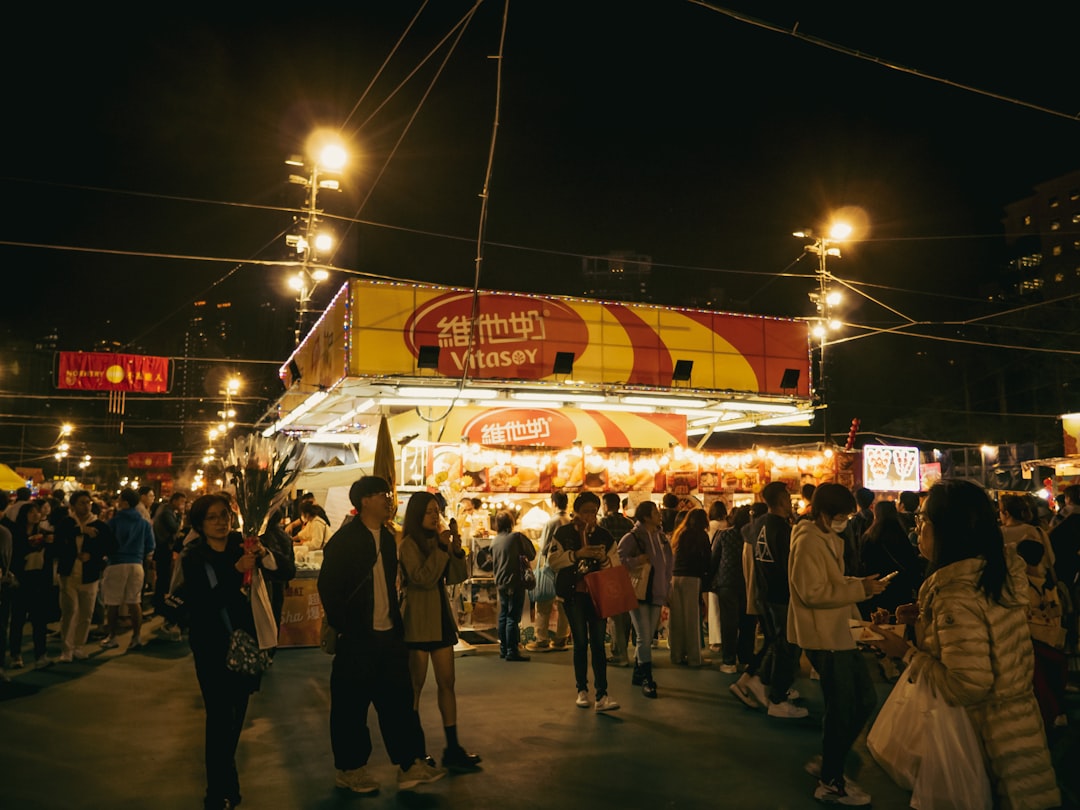 A crowd of people standing around a food stand at night