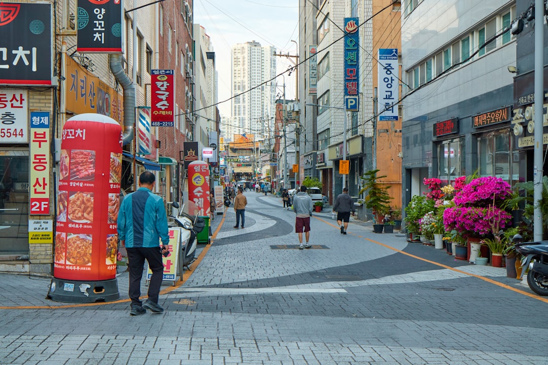 People walking down a narrow street with shops and signs.