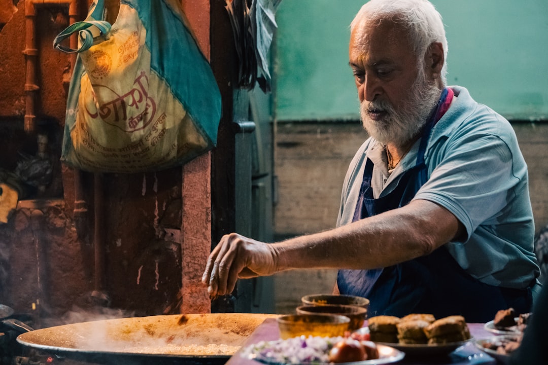 Elderly man cooking food in a busy street stall.