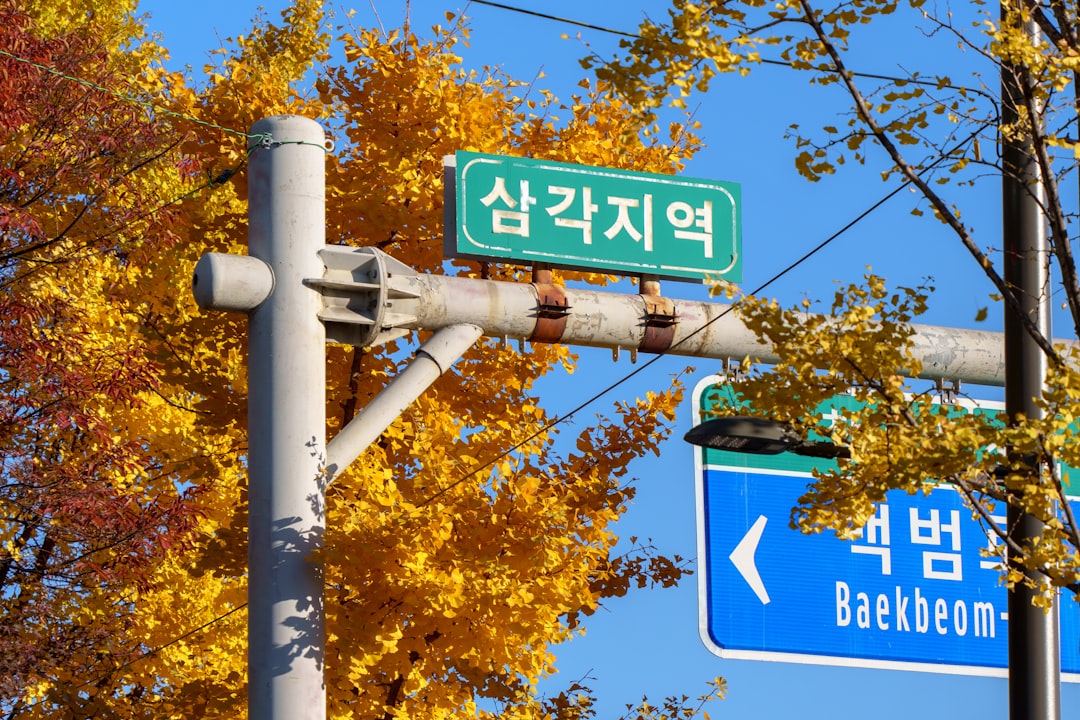 Street sign with autumn trees in the background.
