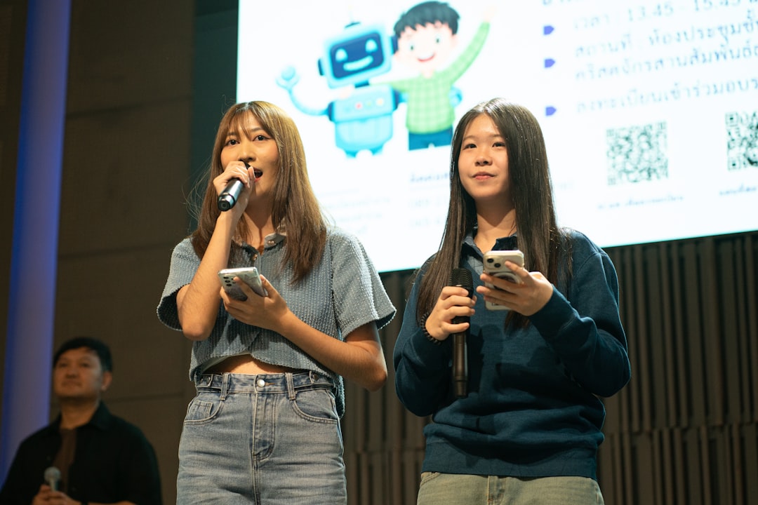 Two young women holding phones on stage.