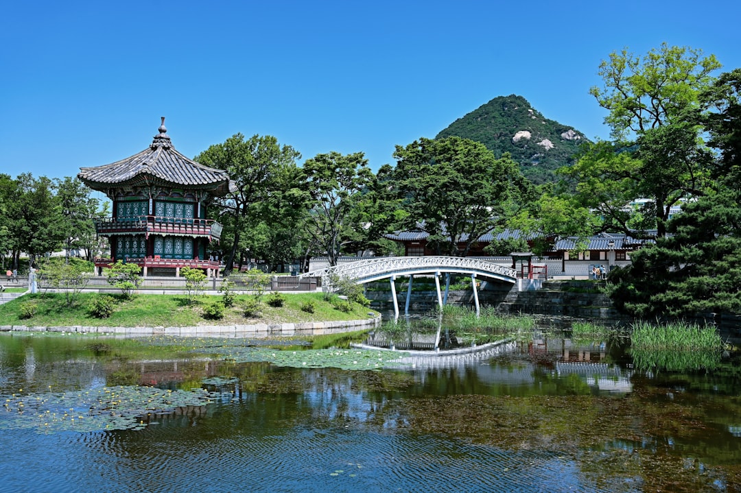 A serene korean pavilion overlooks a reflective lake.