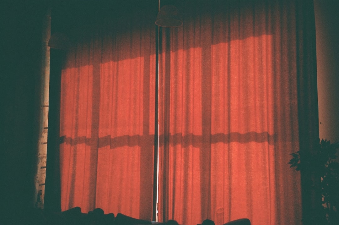 a room with a red curtain and a floor lamp
