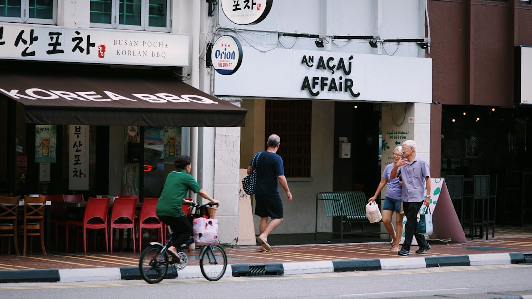 People walk past shops on a sunny day.