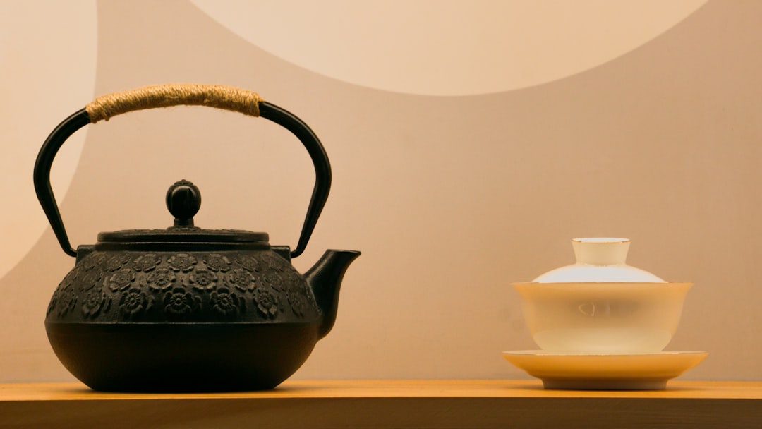 a black tea pot sitting on top of a wooden table