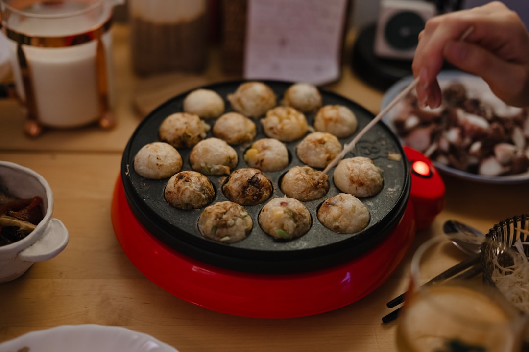 Someone is cooking takoyaki in a takoyaki pan.
