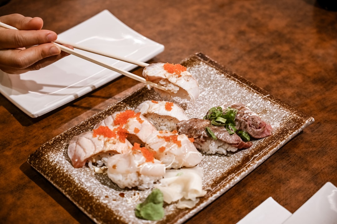 a person holding chopsticks over a plate of food