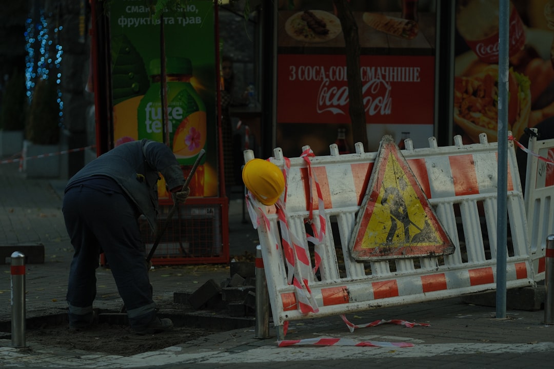 Construction worker digging near a street barrier.
