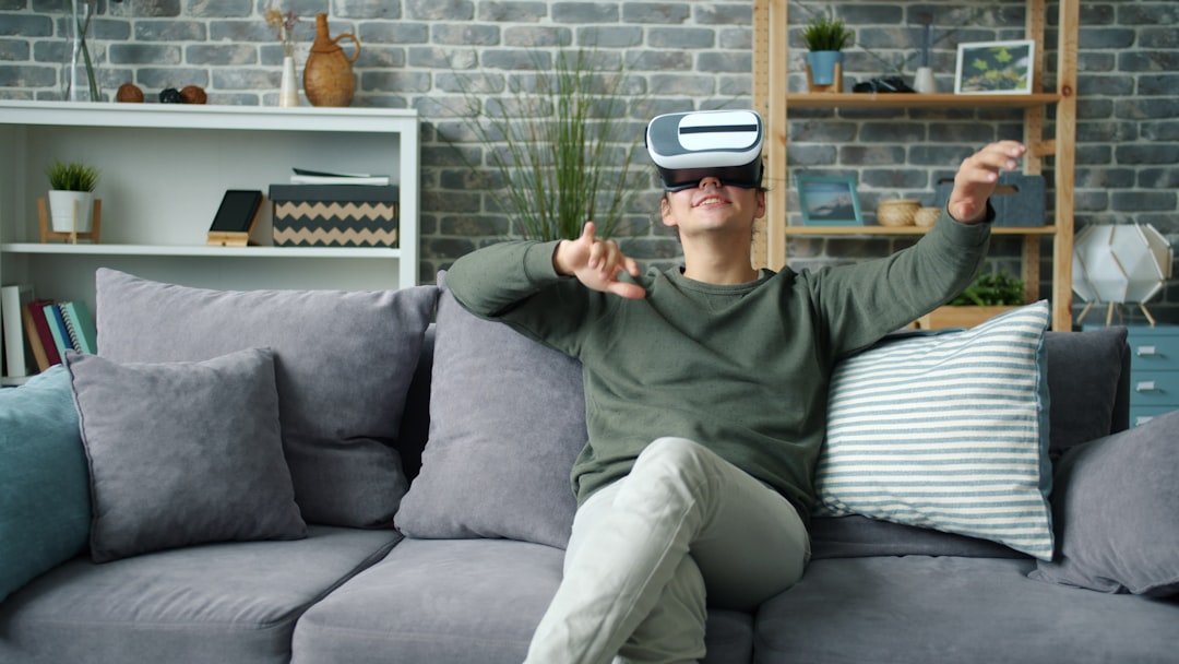 Man wearing vr headset on couch, gesturing with hands gesturing.