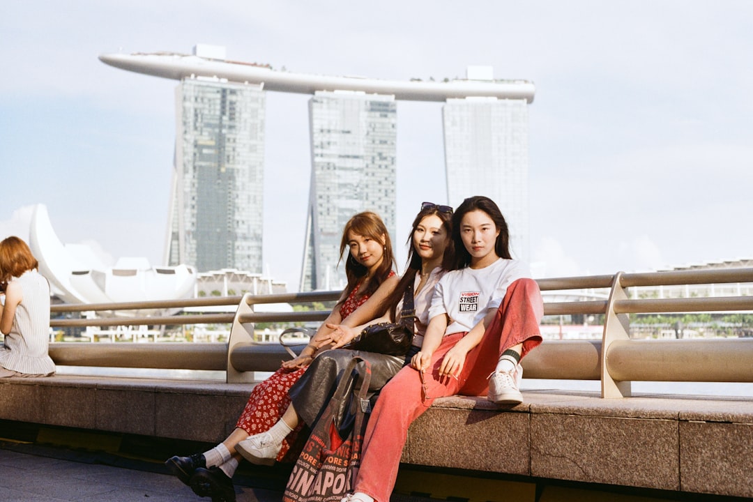 Three women pose with marina bay sands in singapore.